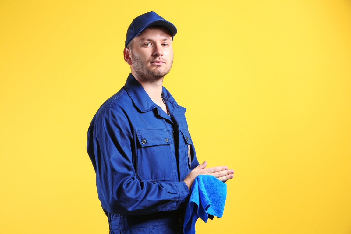 Young Mechanic in Uniform with Rag on Yellow Background